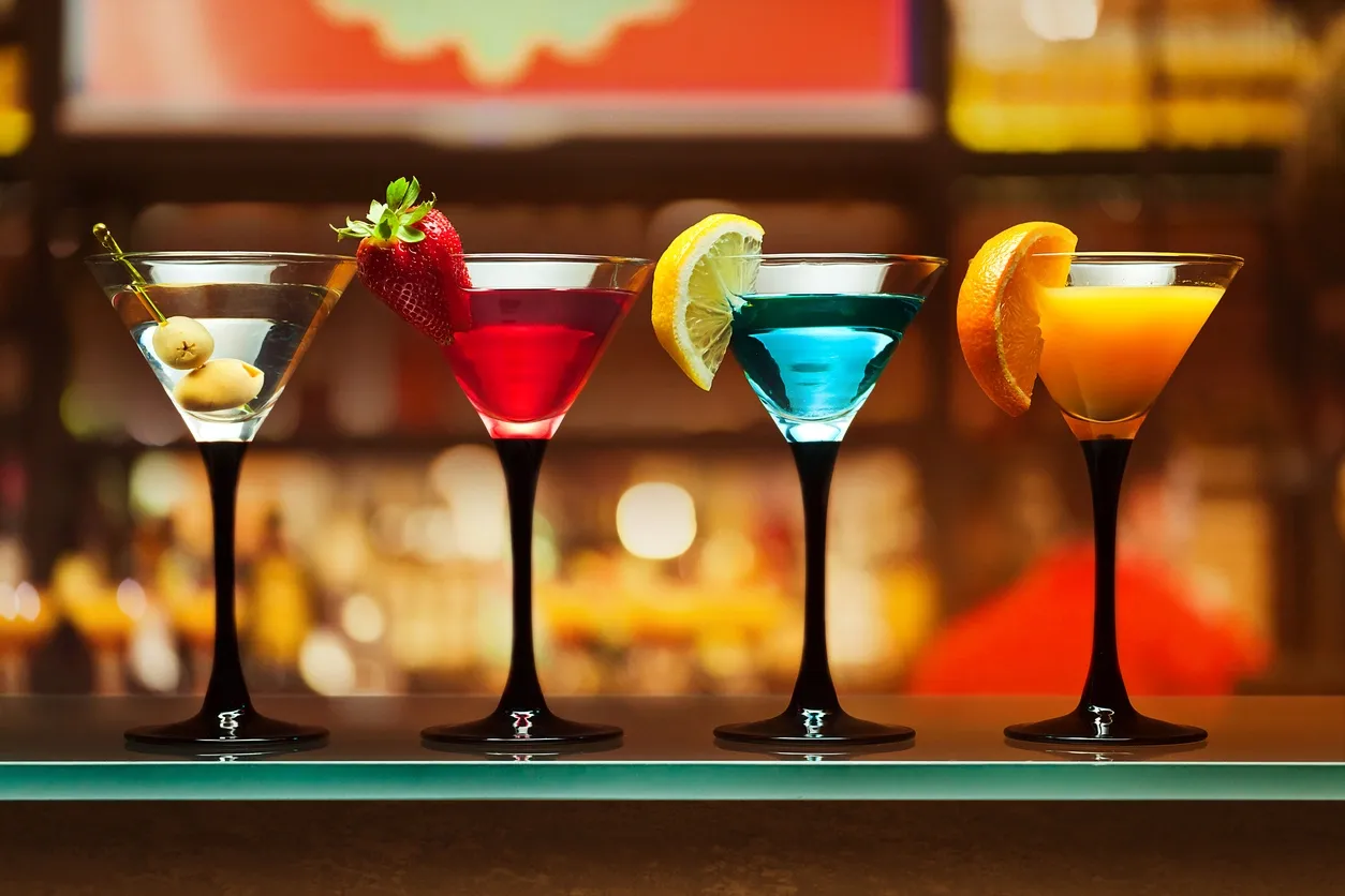 Four colorful cocktails on a bar countertop